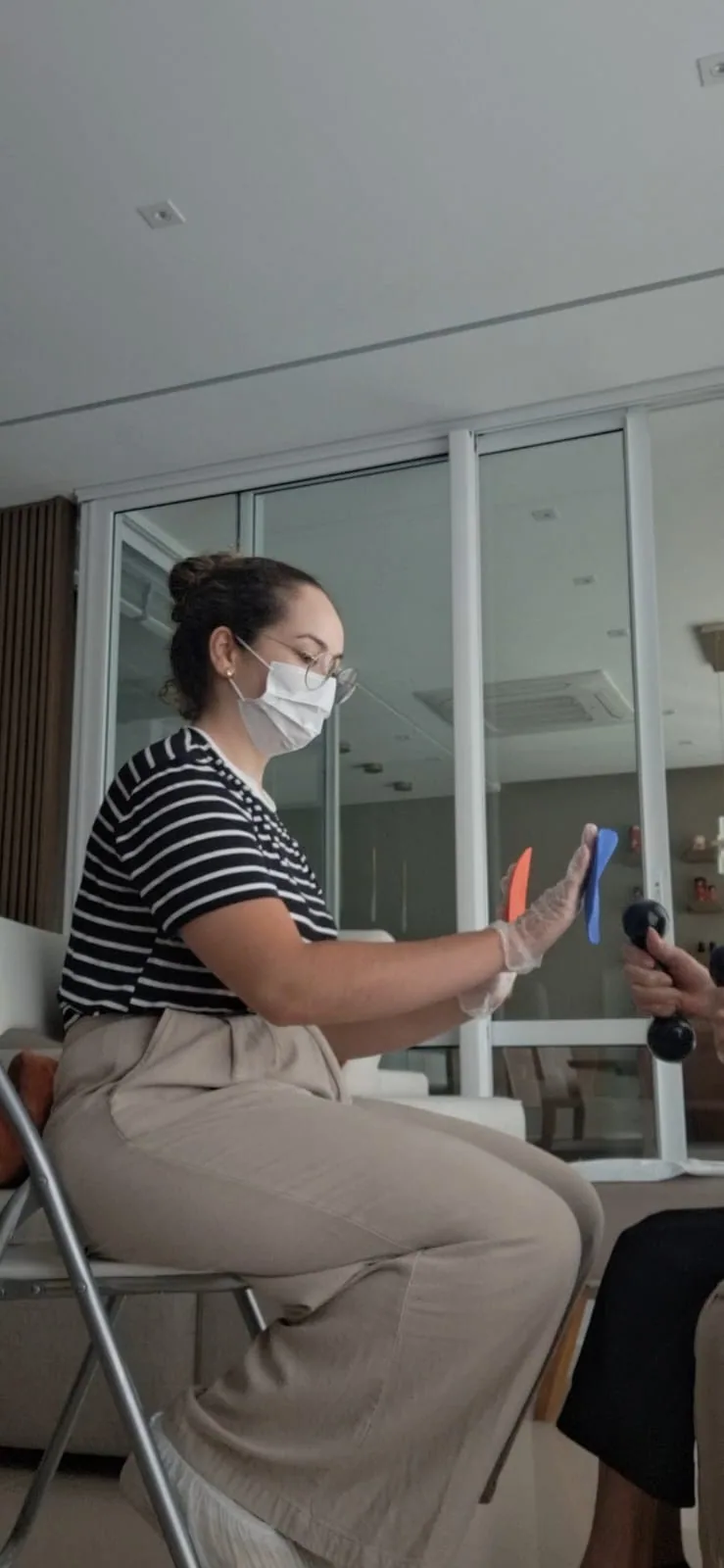 Carina demonstra uma atividade para uma pessoa idosa durante o atendimento em casa.