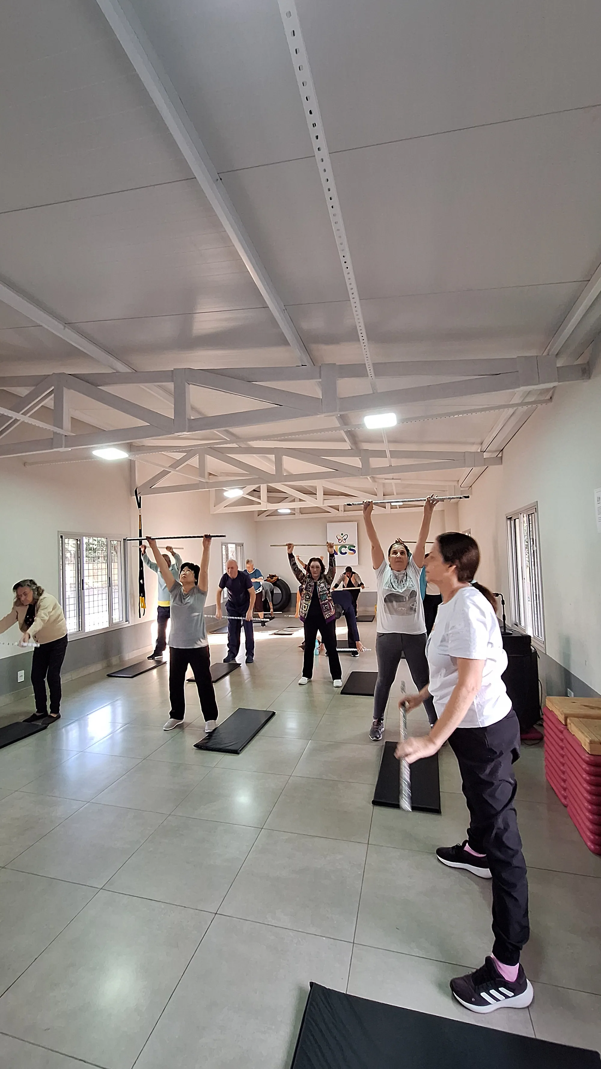 Participantes elevando os braços durante exercício em grupo.